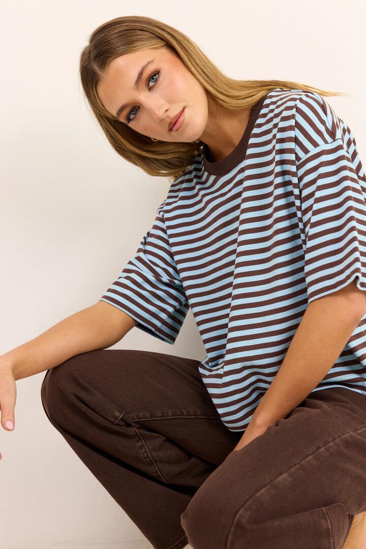 Image of a model wearing Tops. Product name - Cohesion Ice Blue Chocolate Stripe Oversized Contrast Binding Boxy SS Tee in Ice Blue Chocolate Stripe colour by brand - Stories be Told