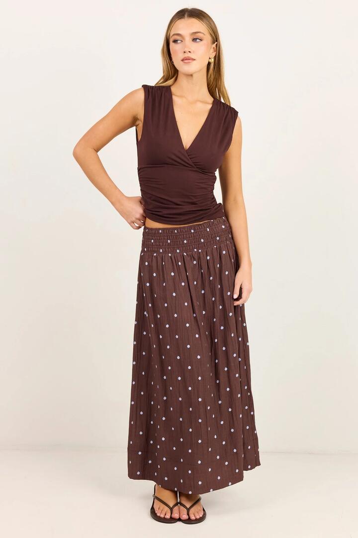 Image of a model wearing Skirts. Product name - Wanderlust Mocha Blue Polka Dot Shirred Waist Maxi Skirt in Mocha Blue Polka Dot colour by brand - Stories be Told