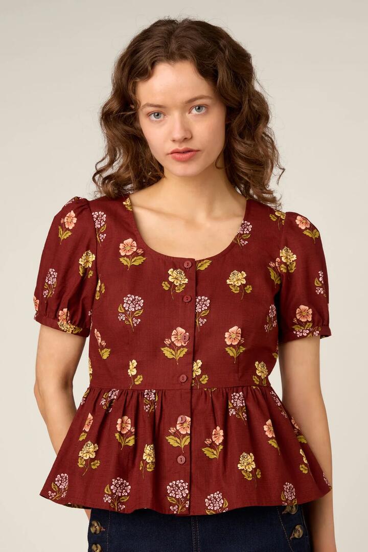 Image of a model wearing Tops. Product name - Meika 90s Flower Peplum Top in Rust colour by brand - Princess Highway