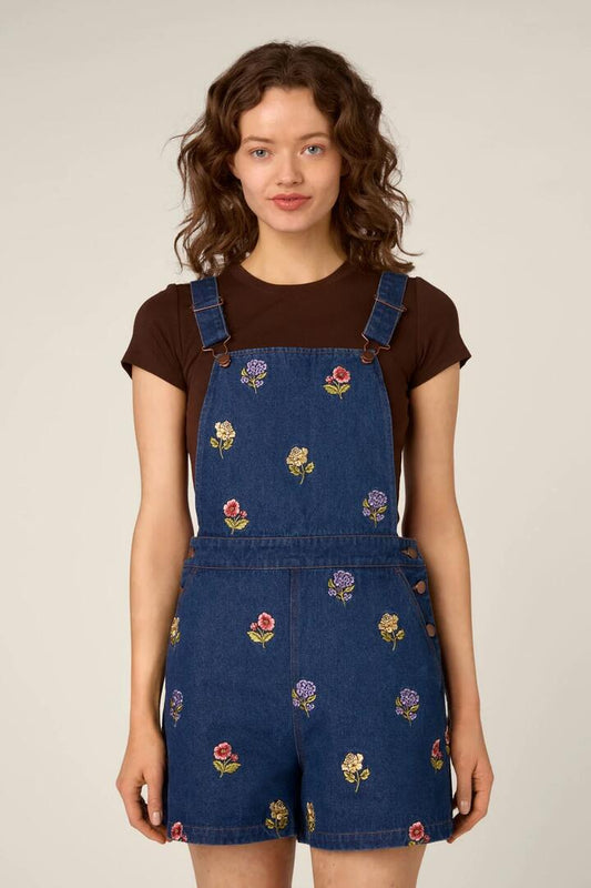 Image of a model wearing Pants. Product name - Meika Flora Short Overall in Blue Denim colour by brand - Princess Highway