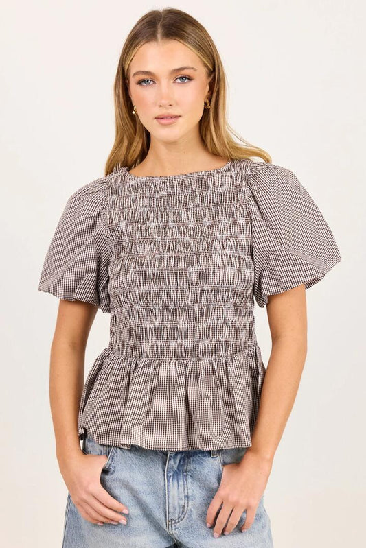 Image of a model wearing Tops. Product name - Artifact Chocolate Mini Gingham Shirred Bubble Sleeve Top in Chocolate Mini Gingham colour by brand - Stories be Told