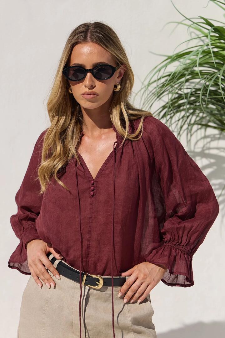Image of a model wearing Tops. Product name - Expedition Burgundy Shirred Neck Short Sleeve Top in Burgundy colour by brand - Among the Brave