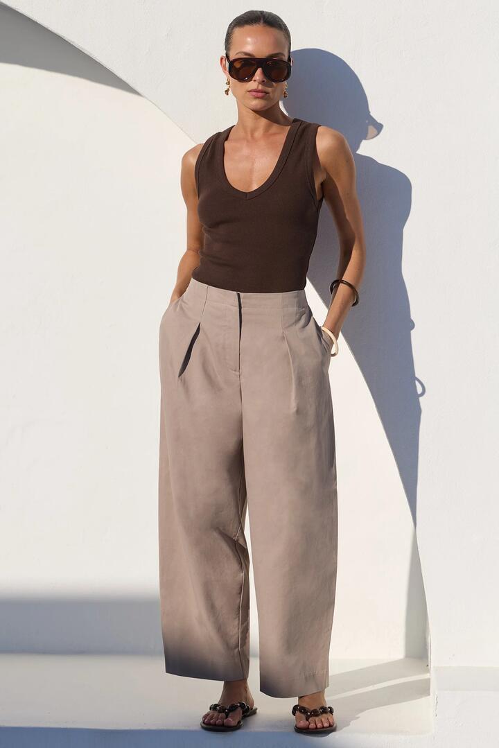 Image of a model wearing Pants. Product name - Manifesto Stone Front Pleat Barrel Leg Pants in Stone colour by brand - Stories be Told