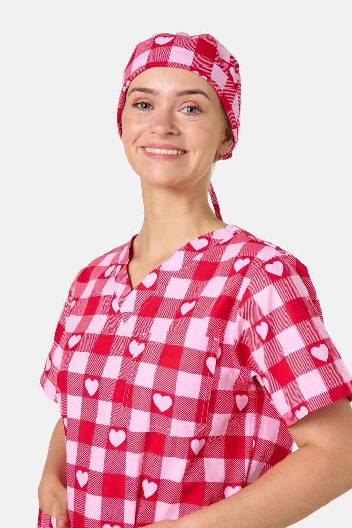 Image of a model wearing Uniforms & Workwear. Product name - Heartbeat Scrub Hat in Pink colour by brand - Scrubs With Love