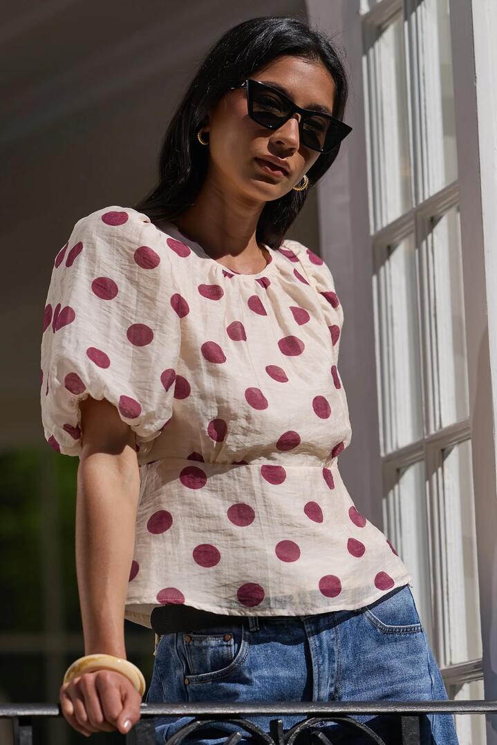Image of a model wearing Tops. Product name - Finali Cream Wine Polka Dot Puff Short Sleeve Top in Cream Wine Polka Dot colour by brand - Stories be Told