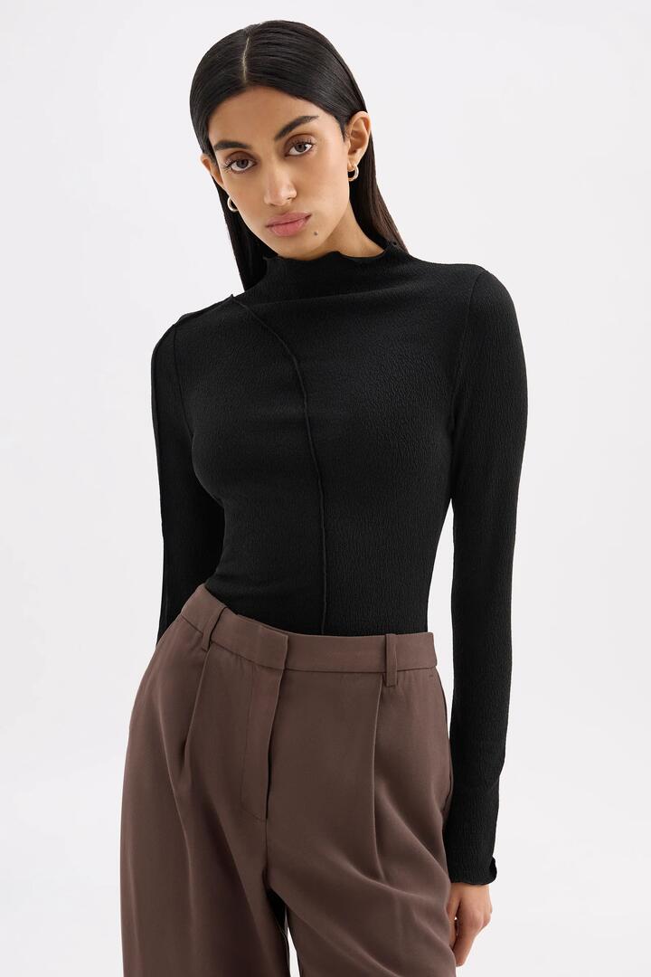 Image of a model wearing Tops. Product name - Mimi Black Front Seam LS Top in Black colour by brand - Nude Lucy