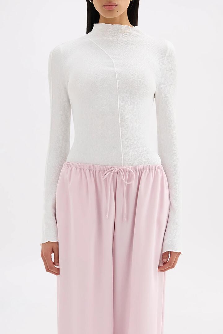 Image of a model wearing Tops. Product name - Mimi Salt Front Seam LS Top in White colour by brand - Nude Lucy