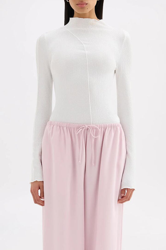 Image of a model wearing Tops. Product name - Mimi Salt Front Seam LS Top in White colour by brand - Nude Lucy