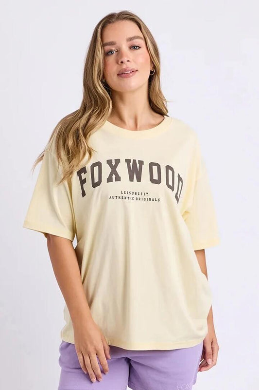 Image of a model wearing Tops. Product name - Interval Butter Cream Choc Logo SS Tee in Yellow colour by brand - Foxwood