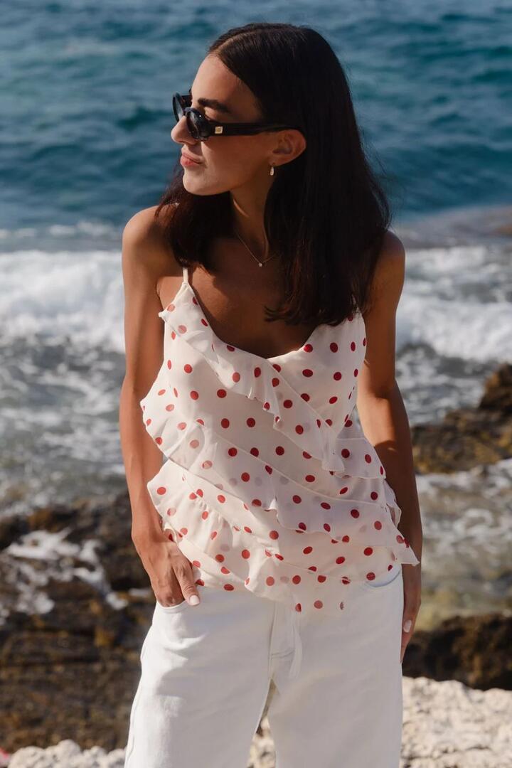 Image of a model wearing Tops. Product name - Outgoing Cream Cherry Polka Dot Frill Front Cami Top in Cream Cherry Polka Dot colour by brand - Georgia Zoe