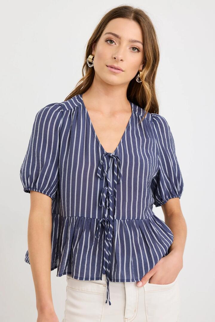 Image of a model wearing Tops. Product name - Restore Navy Stripe Tie Front Peplum SS Top in Navy Stripe colour by brand - Stories be Told