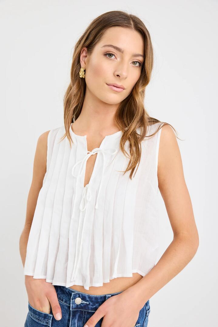 Image of a model wearing Tops. Product name - Origami Ivory Ramie Pleated Sleeveless Tie Top in Ivory Ramie colour by brand - Stories be Told