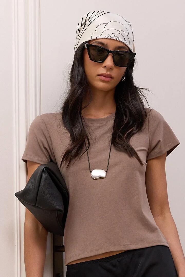 Image of a model wearing Tops. Product name - Observe Mocha Baby Tee in Mocha colour by brand - Stories be Told
