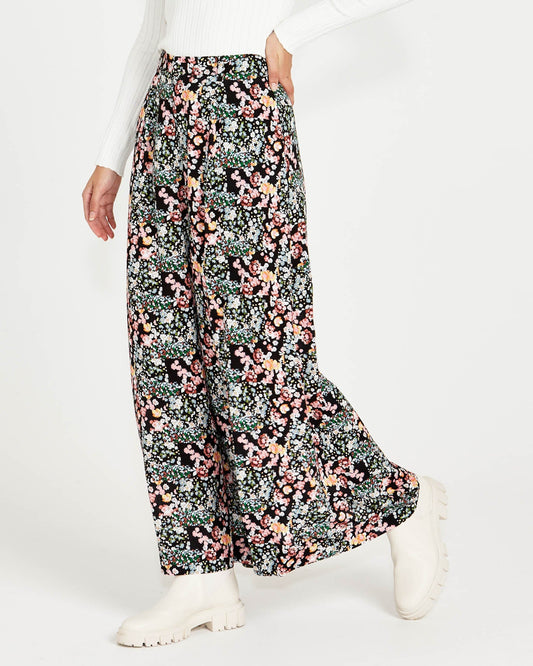 Image of a model wearing Pants. Product name - June Wide Leg Elastic Waist Pant Patchwork Floral Black Multi in Patchwork Floral colour by brand - Sass Clothing