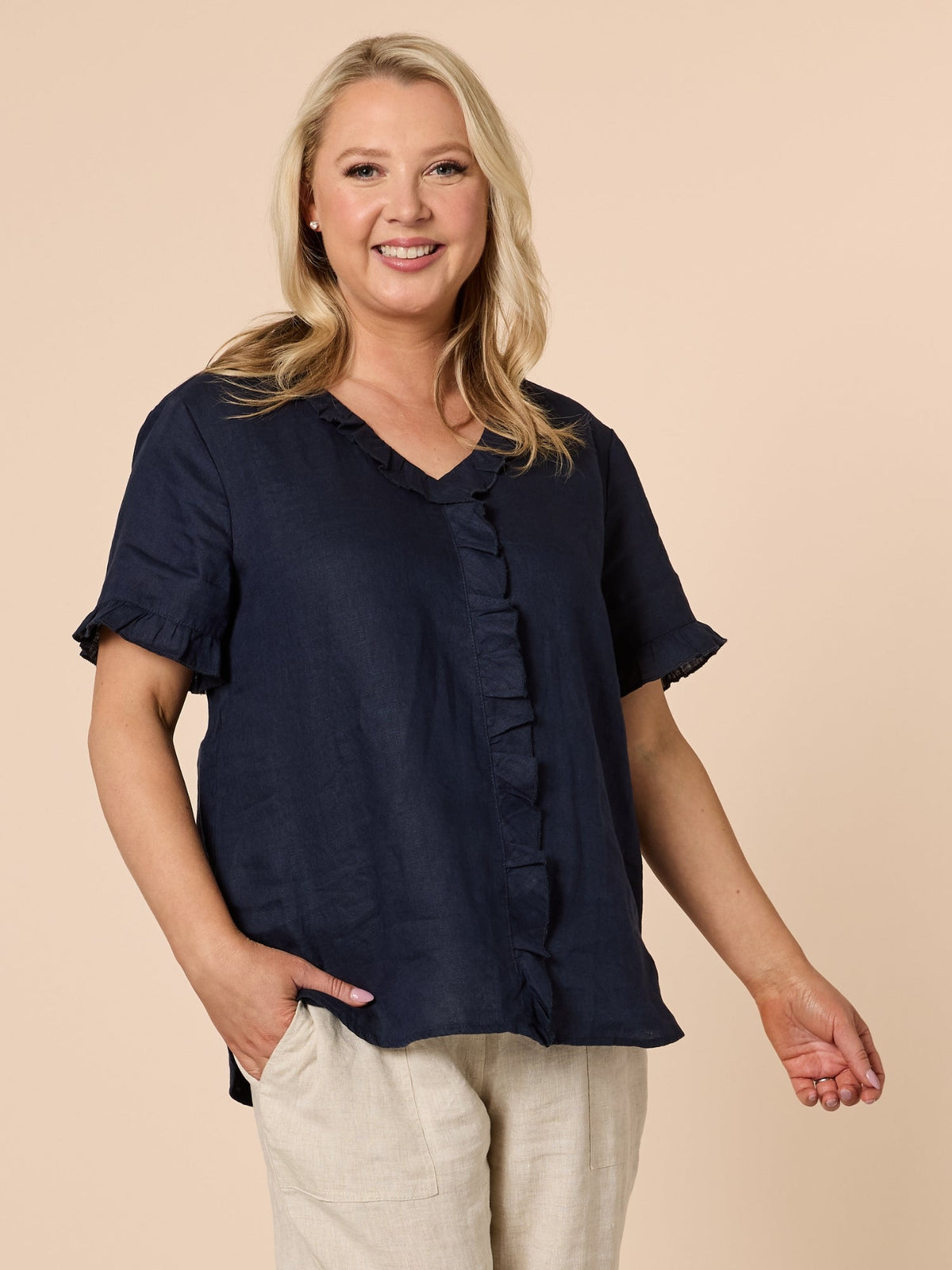 Image of a model wearing Tops. Product name - Tiffany Ruffle Linen Top Navy in Navy colour by brand - Gordon Smith