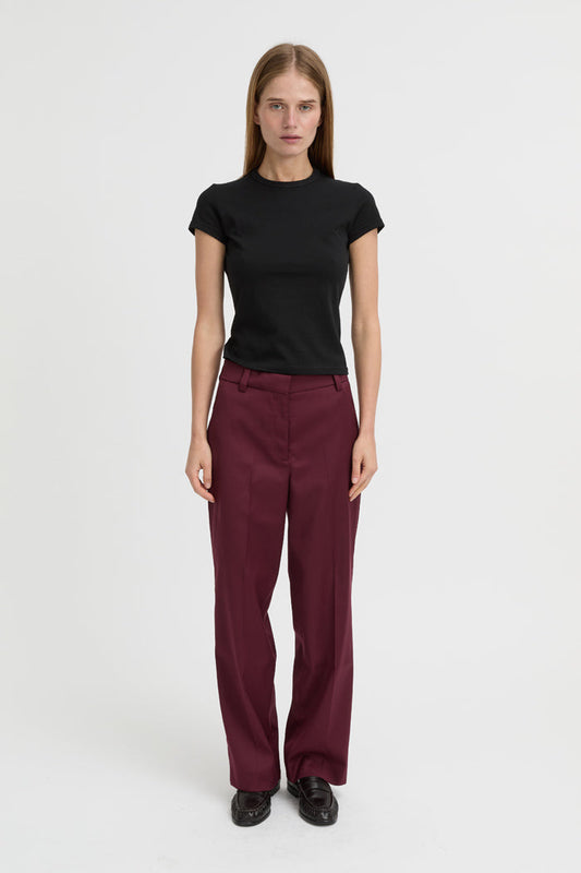 Image of a model wearing Pants. Product name - Blythe Trousers Burgundy in Burgundy colour by brand - Blanca Studio