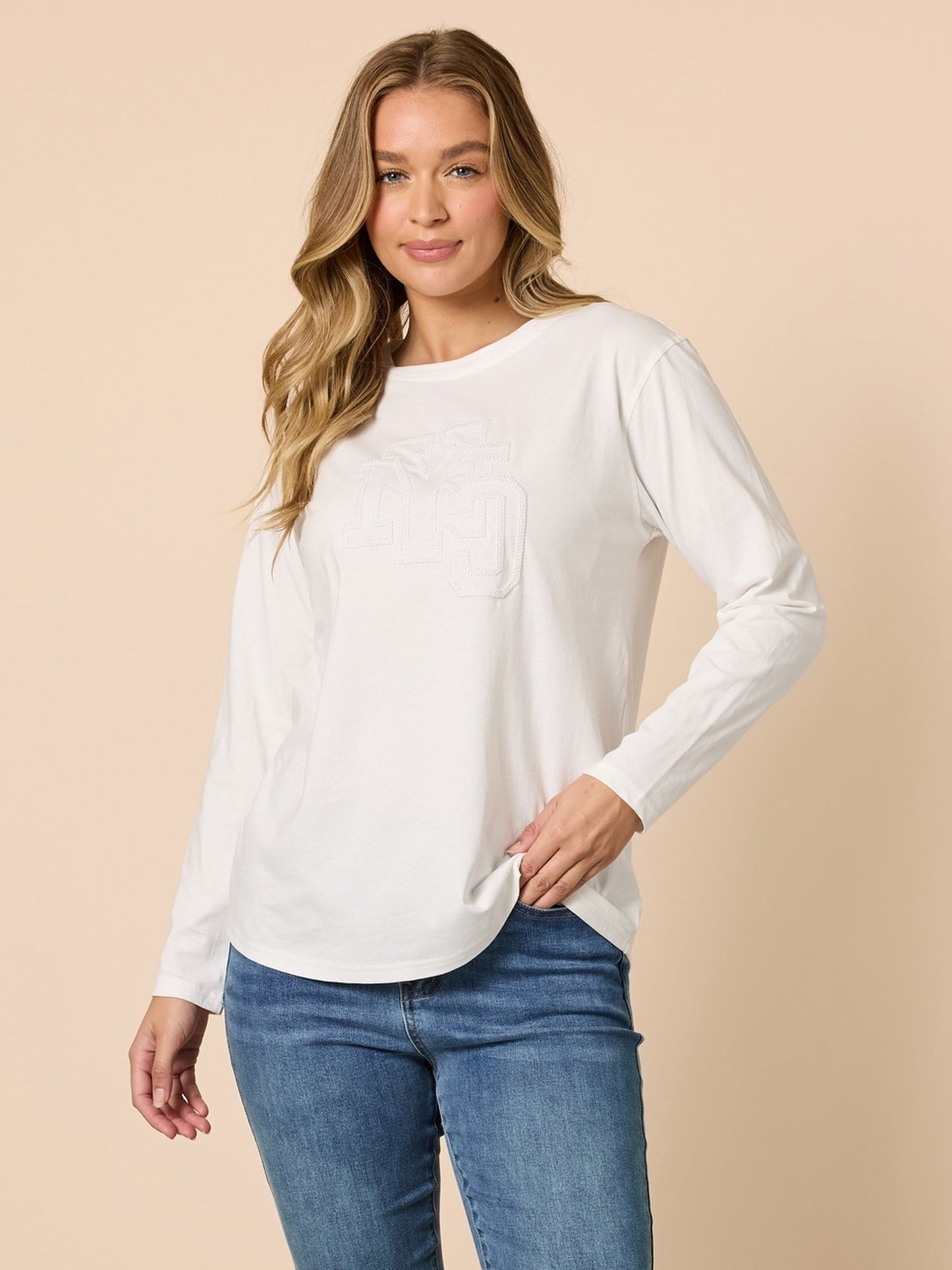 Image of a model wearing Tops. Product name - New York City Embroidered Long Sleeve Tee Ivory in Ivory colour by brand - Threadz