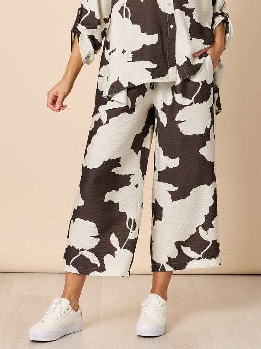 Image of a model wearing Pants. Product name - Toulouse Floral Print Wide Leg Pant Coffee Ivory in Coffee Ivory colour by brand - Clarity
