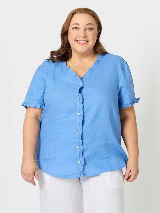 Image of a model wearing Tops. Product name - Audrey Linen Short Sleeve Ruffle Shirt Cornflower in Cornflower colour by brand - Gordon Smith
