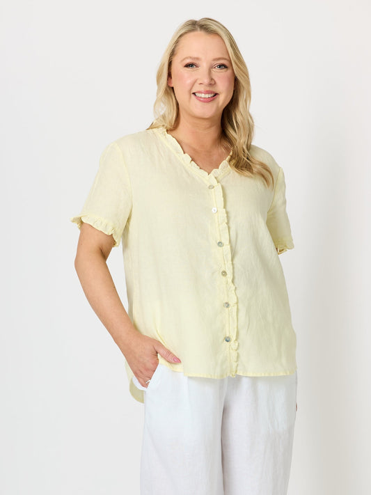 Image of a model wearing Tops. Product name - Audrey Linen Short Sleeve Ruffle Shirt Lemon in Lemon colour by brand - Gordon Smith
