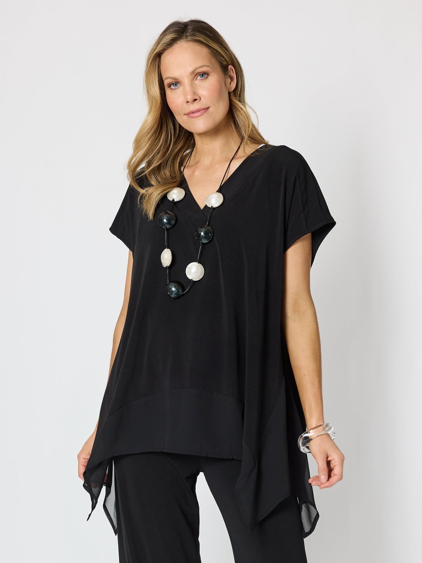 Image of a model wearing Tops. Product name - Traveller Angle Hem Top Black in Black colour by brand - Clarity
