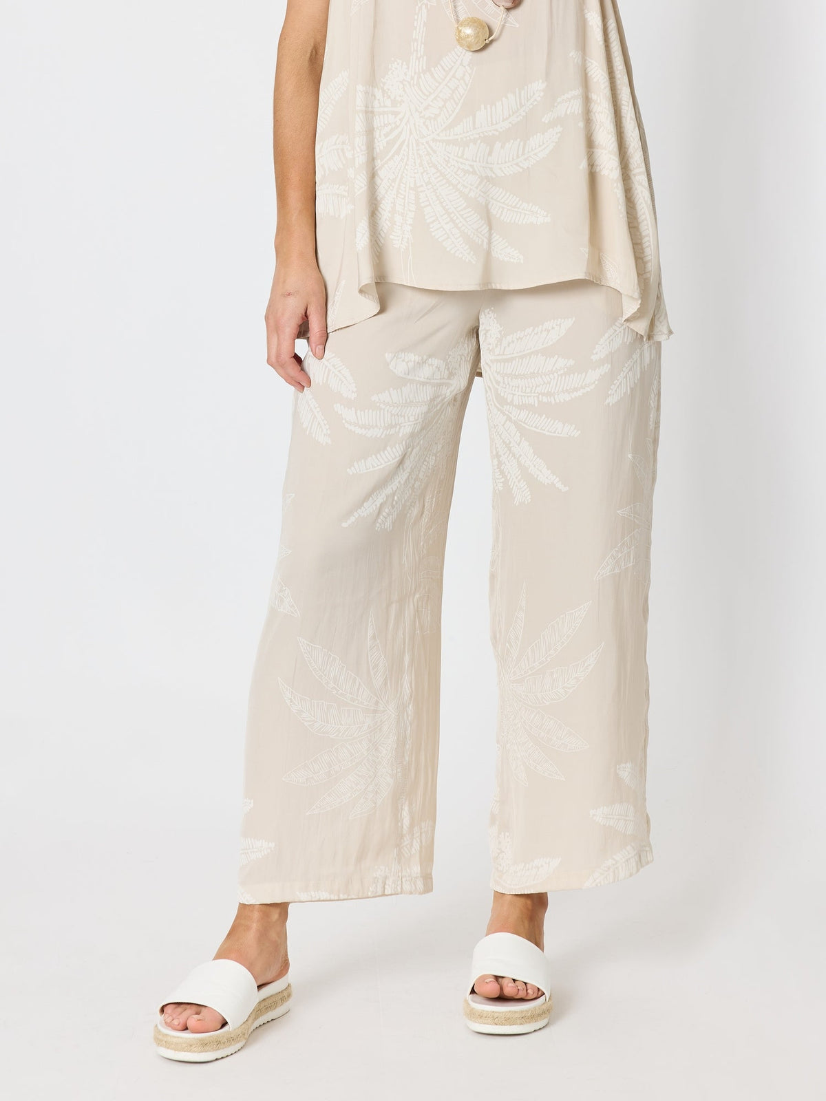 Image of a model wearing Pants. Product name - Sunset Palm Print Wide Leg Pant Natural/White in Natural/White colour by brand - Hammock & Vine