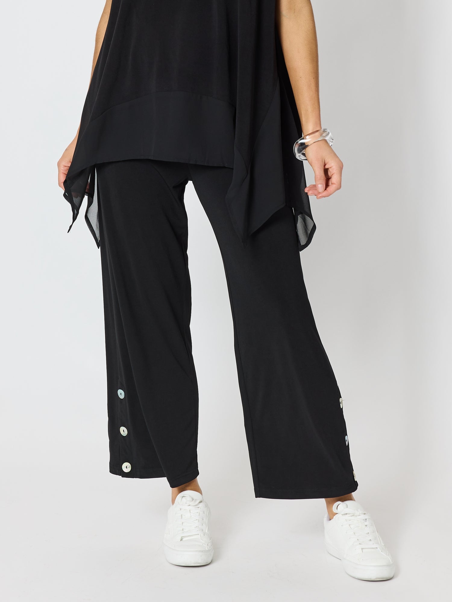 Image of a model wearing Pants. Product name - Traveller Button Hem Pant Black in Black colour by brand - Clarity