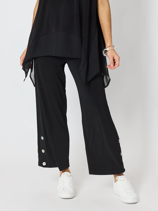 Image of a model wearing Pants. Product name - Traveller Button Hem Pant Black in Black colour by brand - Clarity