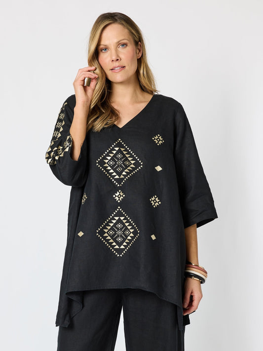 Image of a model wearing Tops. Product name - Soleil Foil Print Linen Top Black/Gold in Black/Gold colour by brand - Hammock & Vine