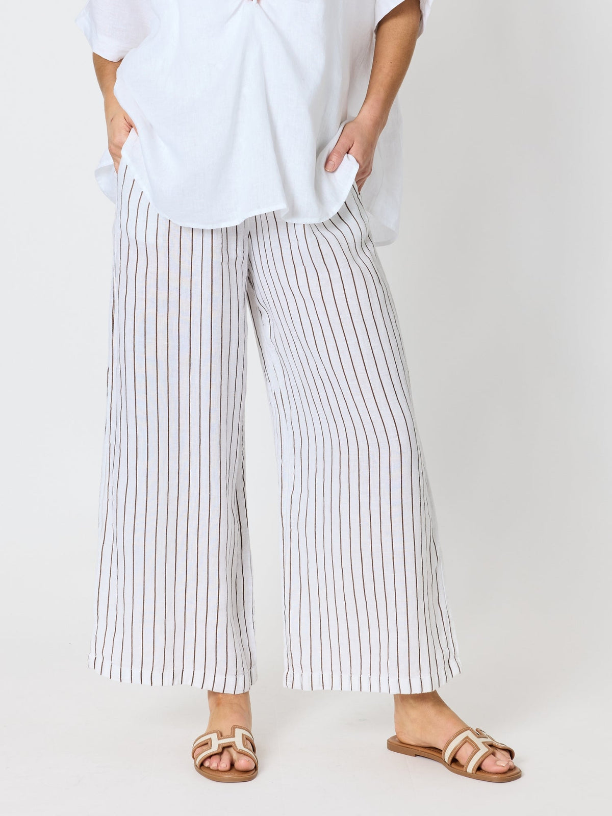Image of a model wearing Pants. Product name - Haven Stripe Wide Leg Linen Pant Mocha White in Mocha White colour by brand - Hammock & Vine