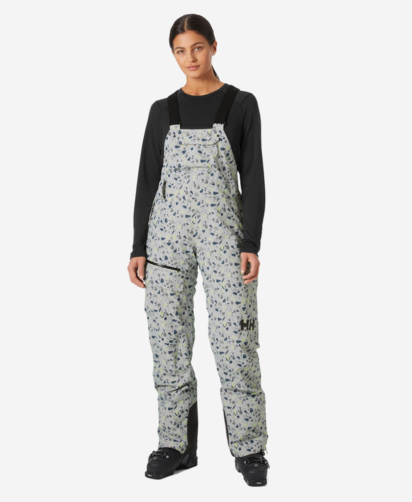 Image of a model wearing Pants. Product name - W POWDERQUEEN BIB PANT, Mellow Grey in Mellow Grey colour by brand - Helly Hansen