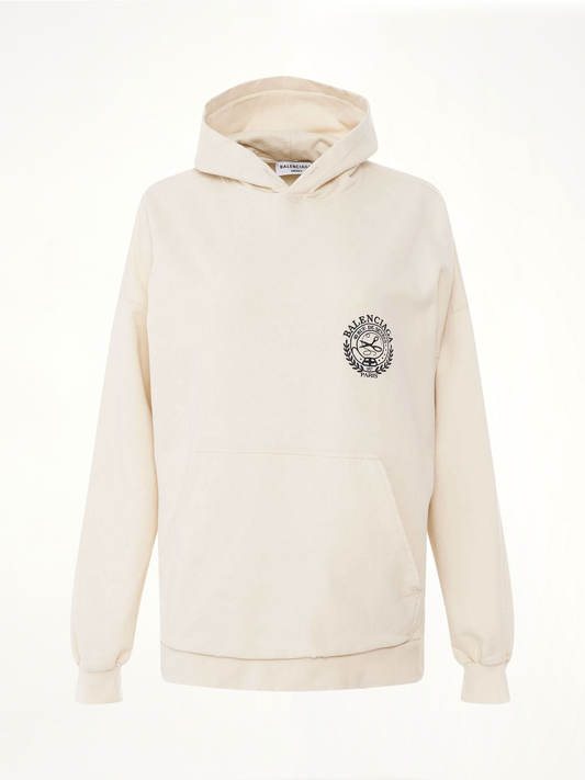Image of a model wearing Outerwear. Productname: BALENCIAGA Scissors Crest Embroidered Wide Fit Hoodie in CREAM colour by brand - BALENCIAGA