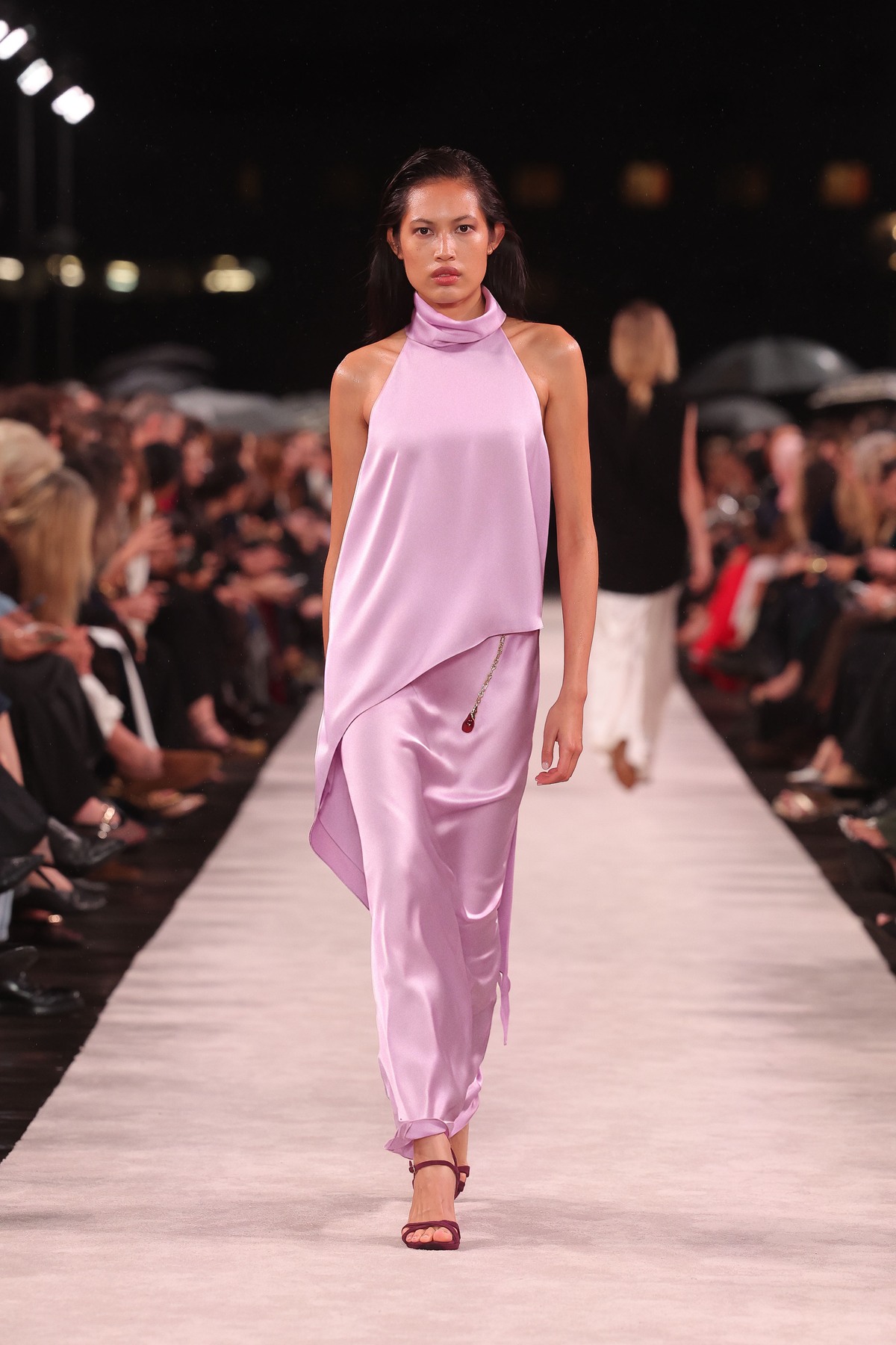 Image of a model wearing Tops. Product name - Floss Lustre Satin Draped Asymmetric Top in Pink colour by brand - Carla Zampatti
