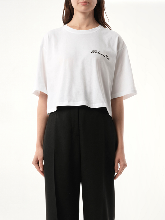 Image of a model wearing Tops. Product name - Balmain Signatured Embroidered Crop Top in White colour by brand - BALMAIN