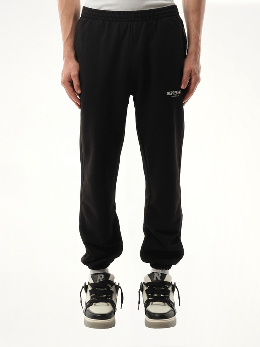 Image of a model wearing Pants. Product name - Represent Owners Club Sweatpants in Black colour by brand - REPRESENT