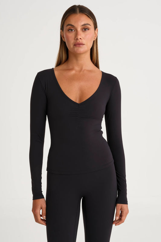 Image of a model wearing Tops. Product name - ALLFENIX CloudCore Lite Ruched V-Neck Long Sleeve in Black colour by brand - All Fenix