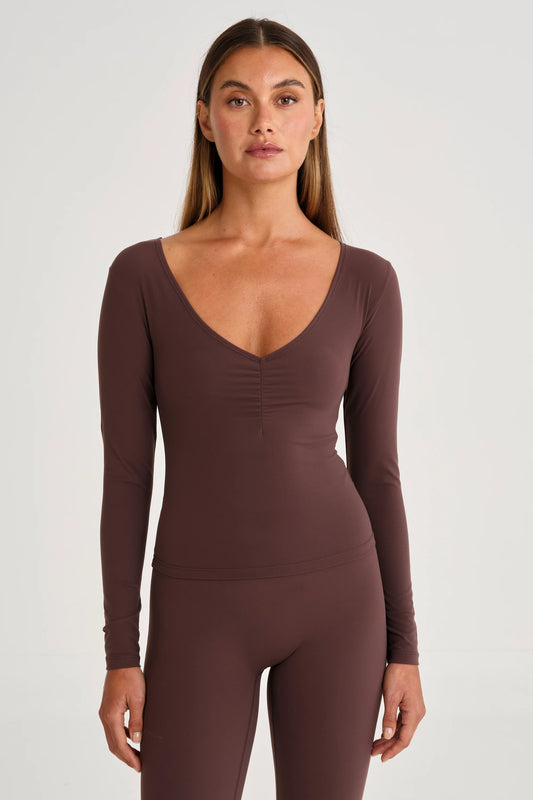 Image of a model wearing Tops. Product name - ALLFENIX CloudCore Lite Ruched V-Neck Long Sleeve in Espresso colour by brand - All Fenix