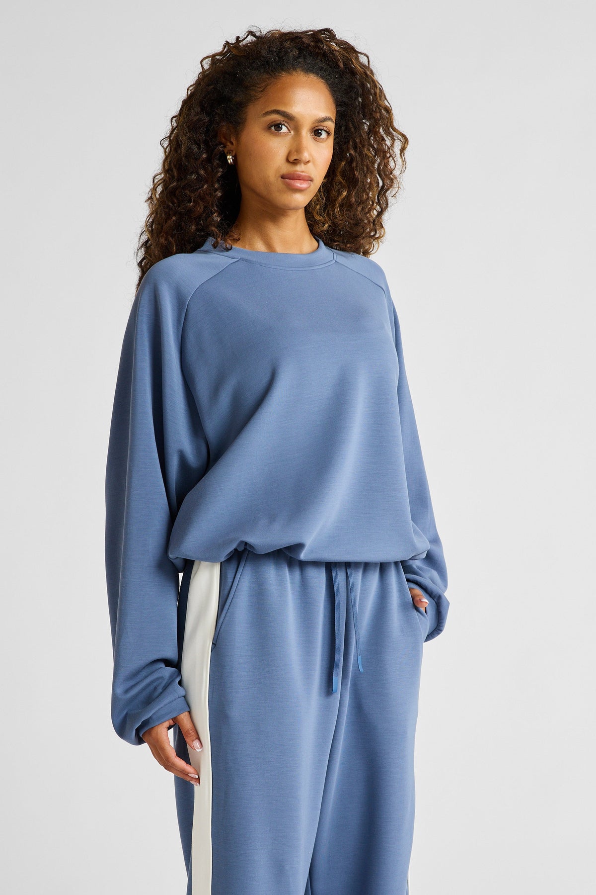 Image of a model wearing Outerwear. Product name - Soft Essentials Cropped Crew Neck Jumper in Blue colour by brand - All Fenix