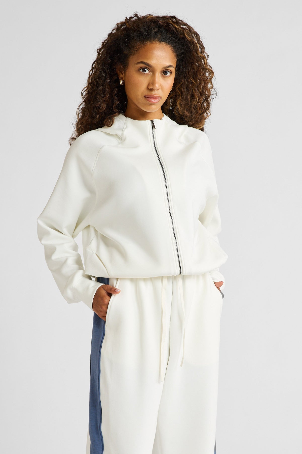 Image of a model wearing Outerwear. Product name - Soft Essentials Cropped Hoodie in Chalk colour by brand - All Fenix