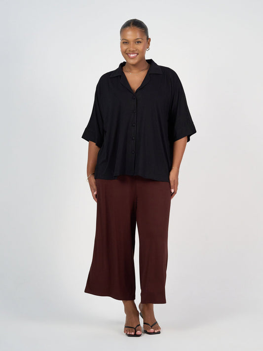 Image of a model wearing Tops. Product name - Alanis 3/4 Sleeve Collared Bamboo Shirt Black in Black colour by brand - Lou Lou