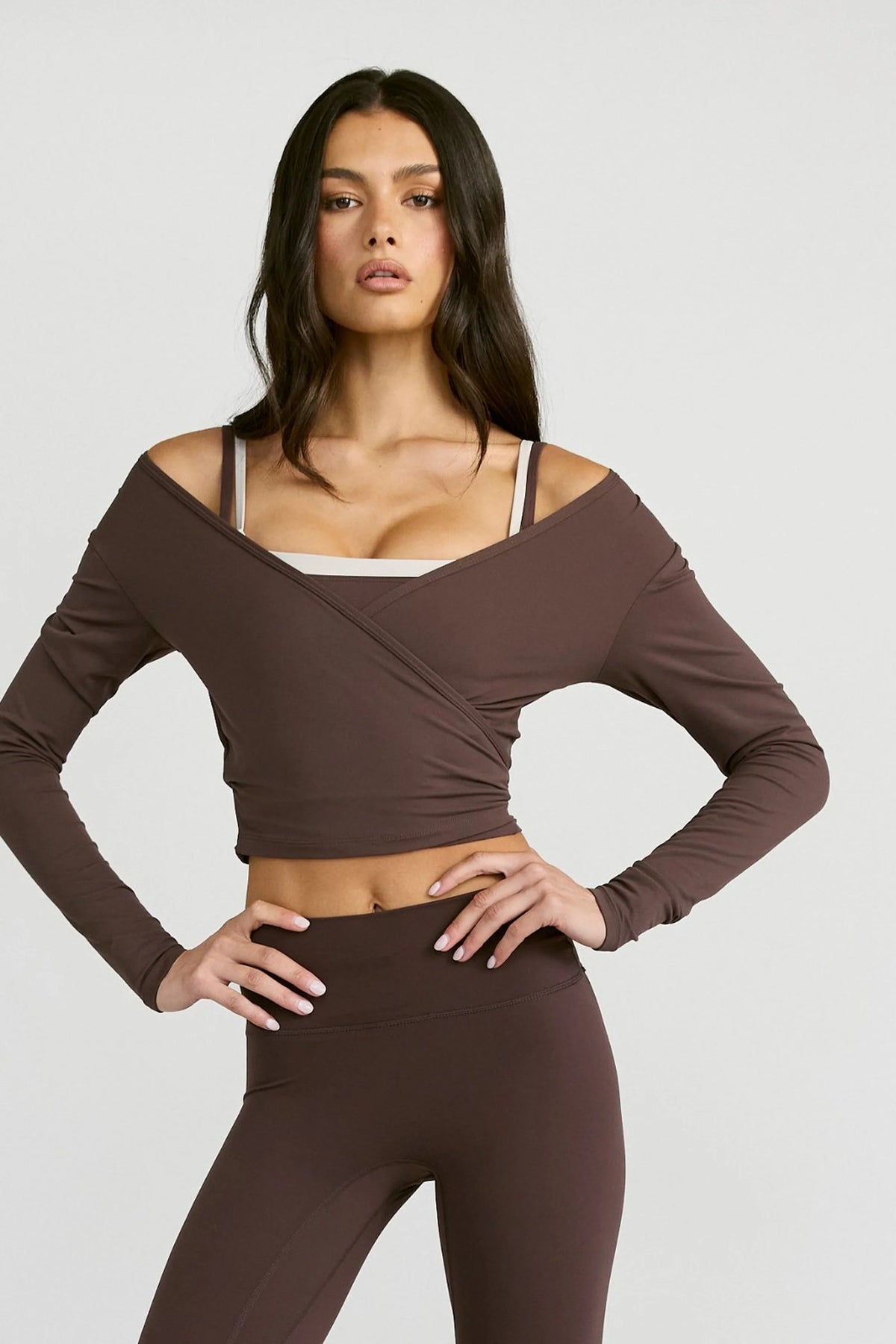 Image of a model wearing Tops. Product name - ALLFENIX CloudCore Lite Long Sleeve Wrap Top in Espresso colour by brand - All Fenix