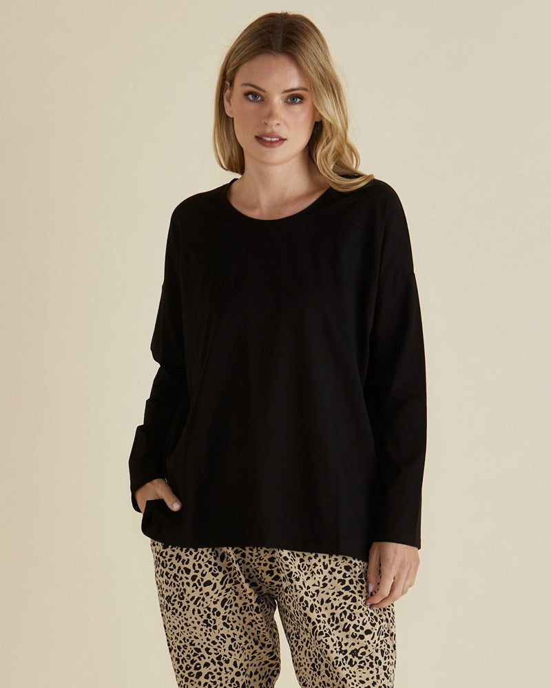 Image of a model wearing Tops. Product name - Brixley Long Sleeve Top Black in Black colour by brand - Betty Basics