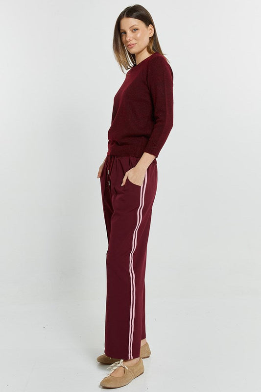 Image of a model wearing Pants. Product name - Maddison Jogger Wine in Wine colour by brand - Betty Basics