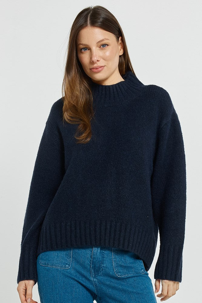 Image of a model wearing Outerwear. Product name - Lola Jumper Navy in Navy colour by brand - Betty Basics