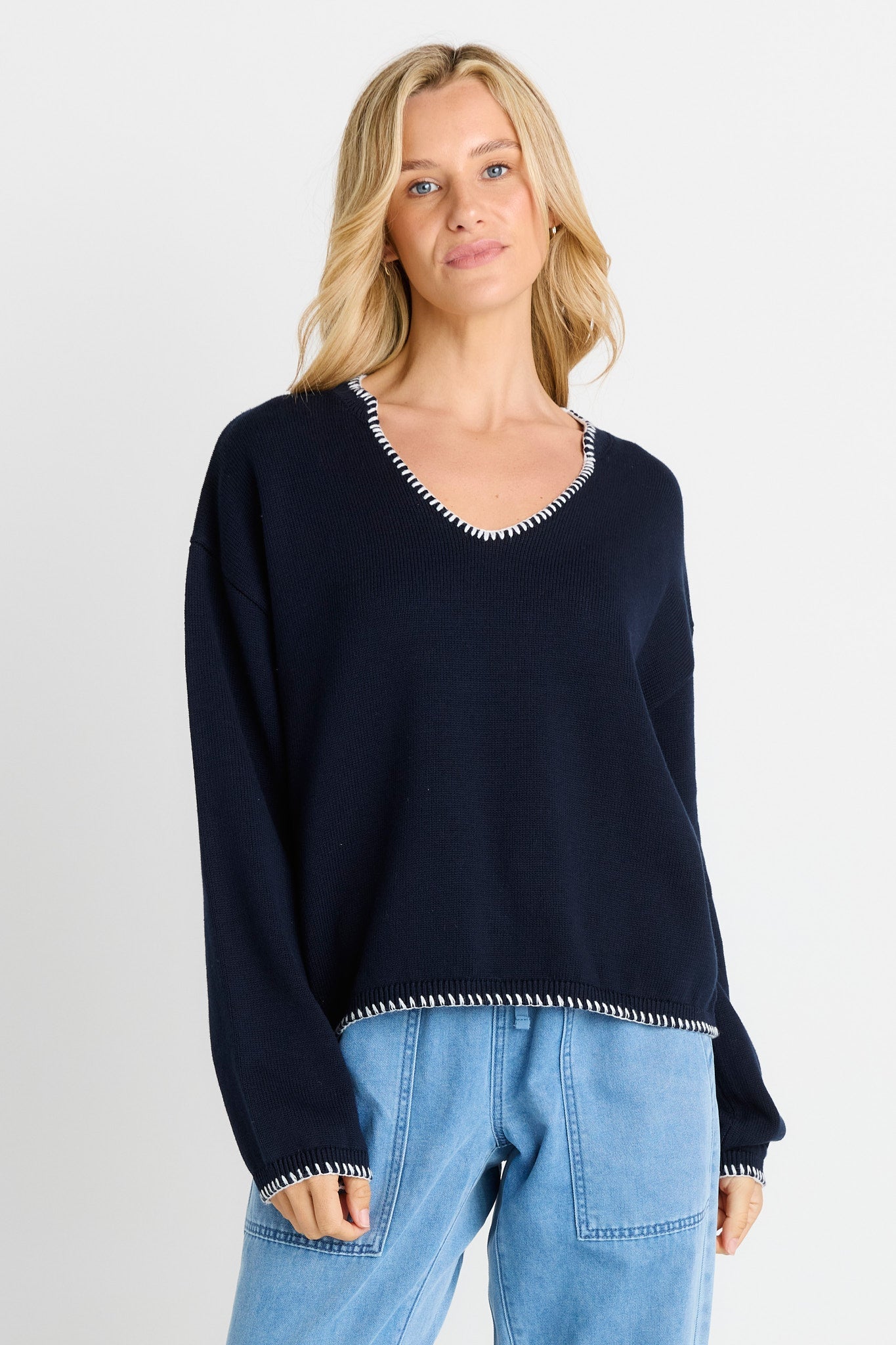 Image of a model wearing Outerwear. Product name - Ascot Stitch Sweater Navy in Navy colour by brand - Betty Basics