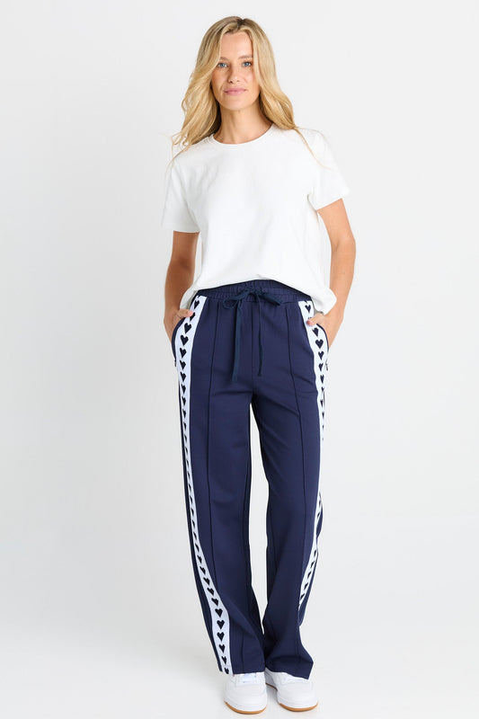 Image of a model wearing Pants. Product name - Jamie Trackpant Navy in Navy colour by brand - Betty Basics