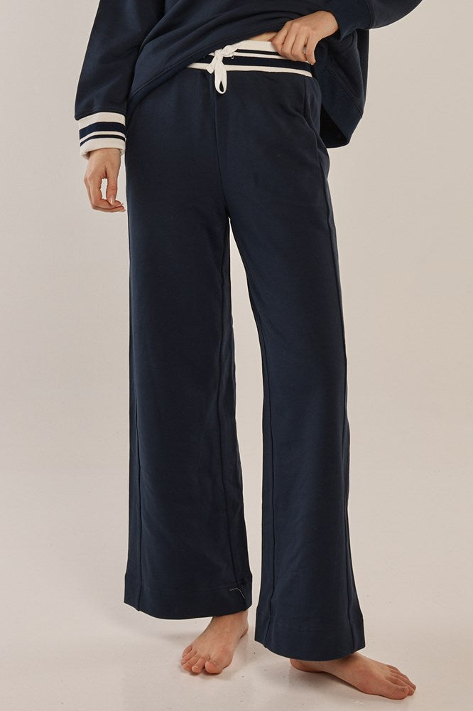 Image of a model wearing Pants. Product name - Rhiannon Trackpant Navy in Navy colour by brand - Betty Basics