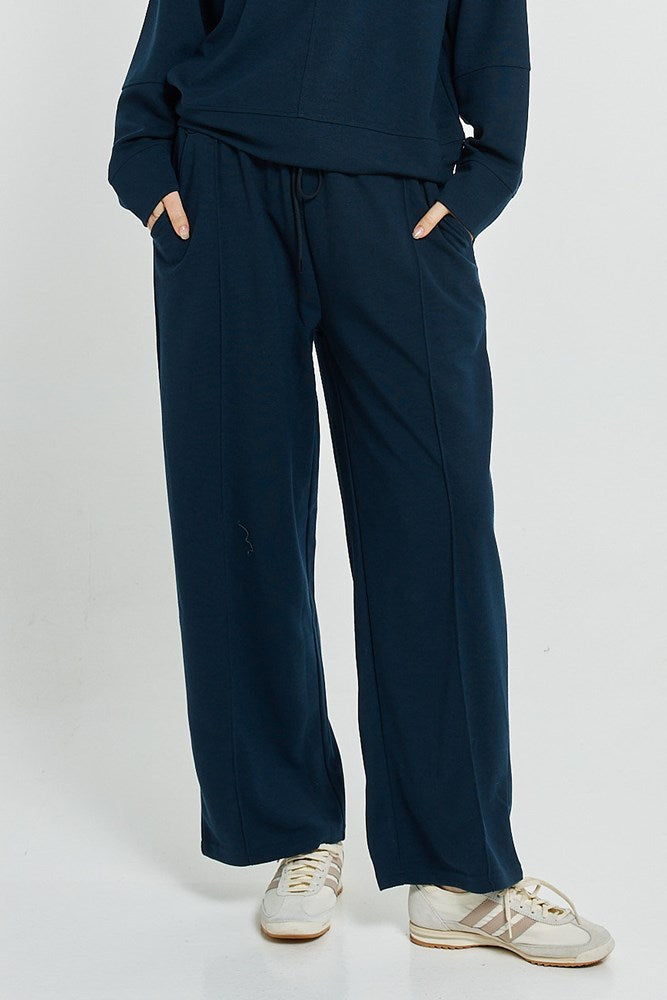 Image of a model wearing Pants. Product name - Elona Jogger Navy in Navy colour by brand - Betty Basics