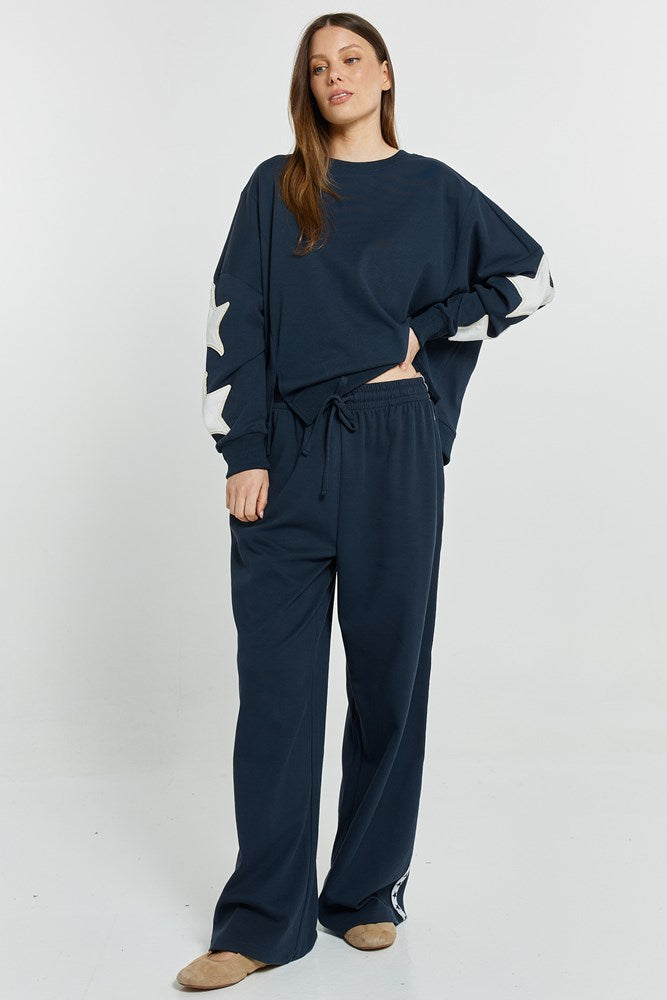 Image of a model wearing Pants. Product name - Saskia TrackPant Navy in Navy colour by brand - Betty Basics