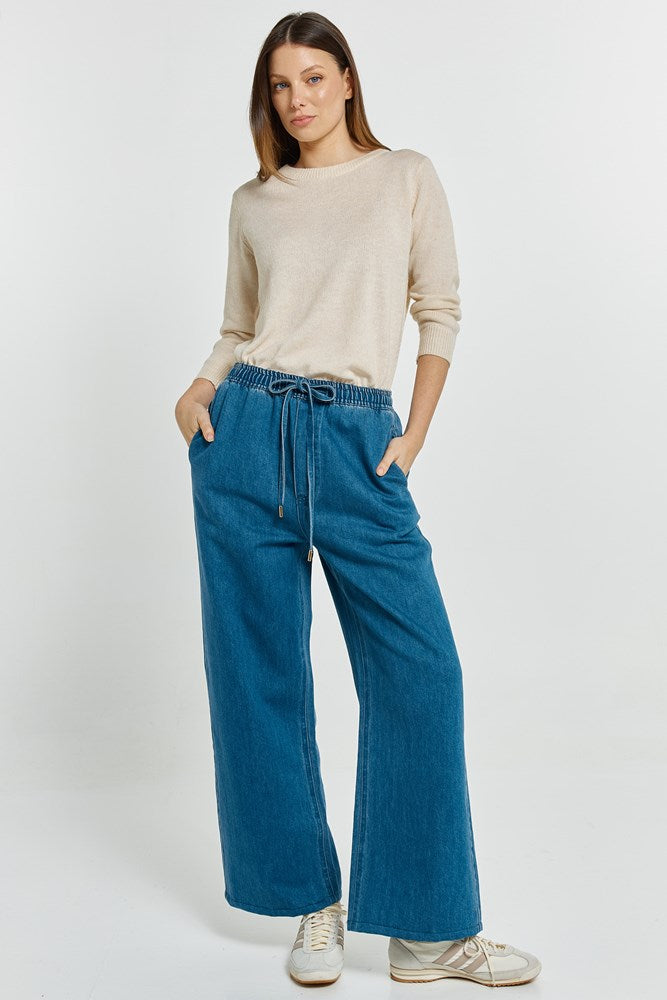 Image of a model wearing Pants. Product name - Vespa Denim Jogger Mid Blue in Mid Blue colour by brand - Betty Basics